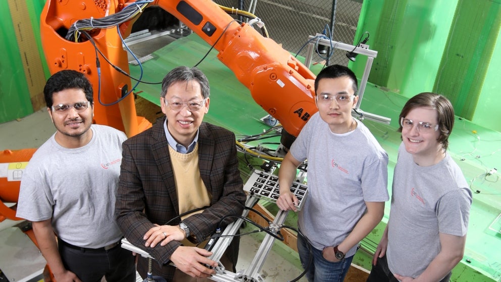 John Wen and team standing in front of robotic arm