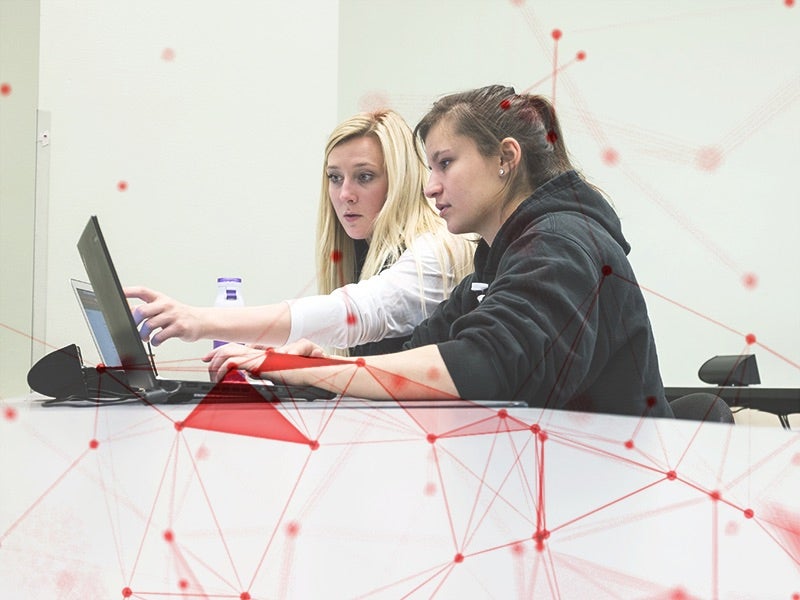 Two girls working at laptops