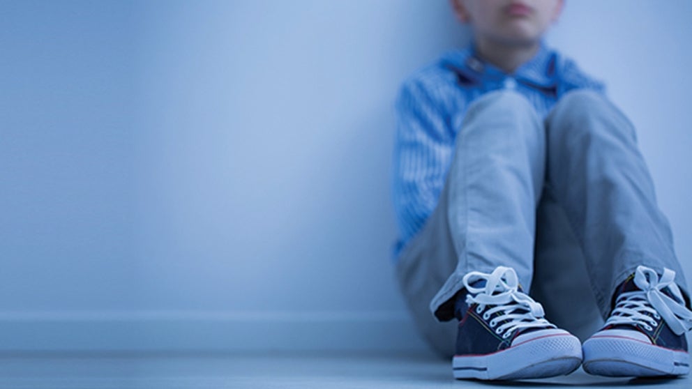 Young boy leaning against a wall