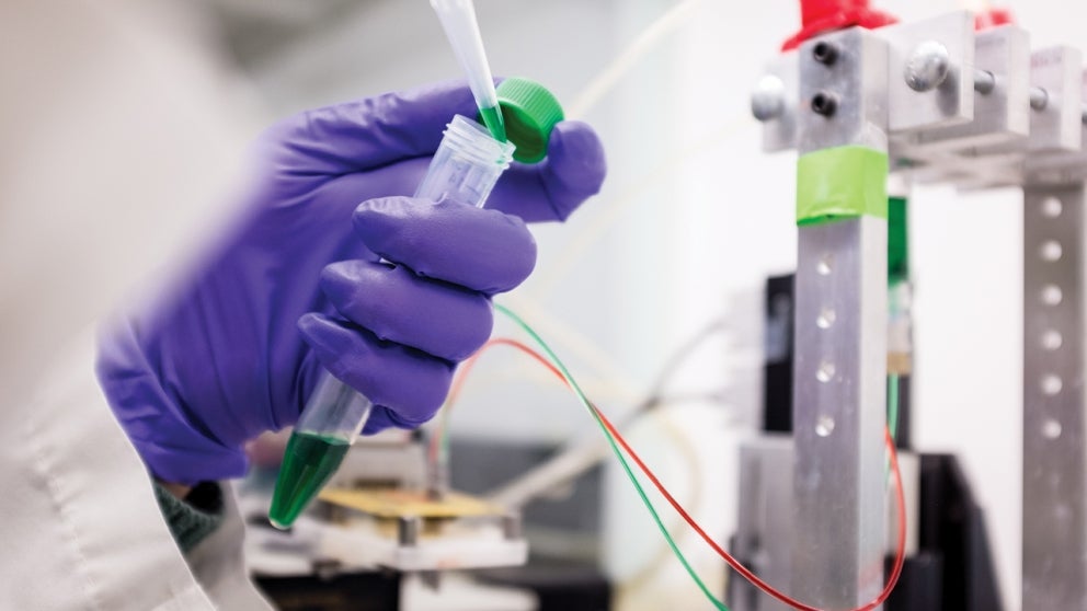 Hand holding a test tube being filled with liquid via a pipette