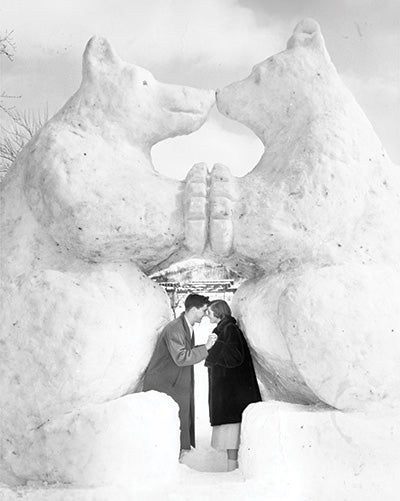 Two alumns pose under giant polar bear ice sculpture