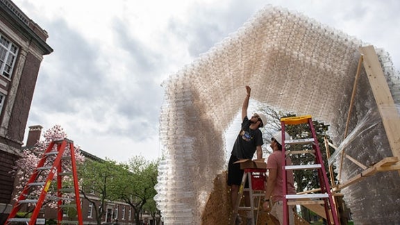 Students finish building a shelter made from water bottles