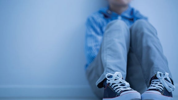 Young boy leaning against a wall