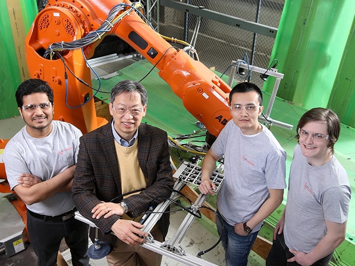 John Wen and team with robotic manufacturing arm in background