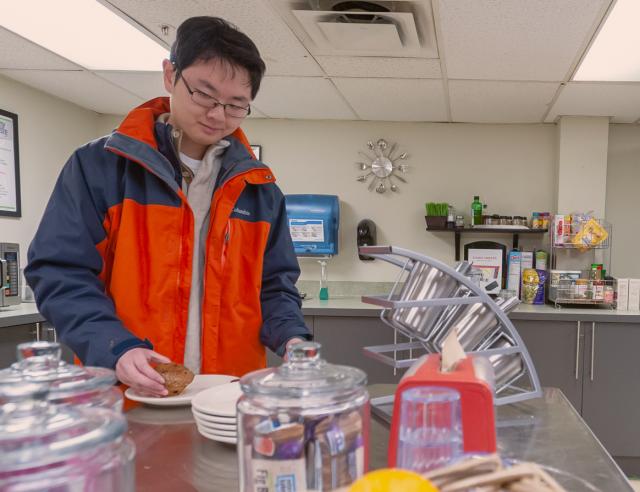 Student prepares food in commons dining area