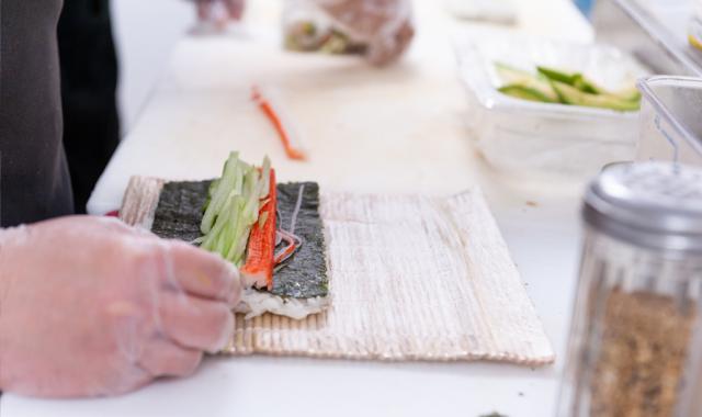 Close-up of a hand rolling sushi