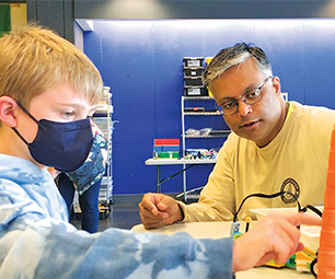 Child wearing a face mask builds with legos as Paras Patani advises